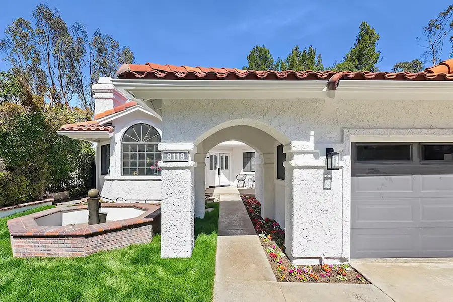 Exterior of a home with a white facade, terracotta tile roof, and landscaped garden.