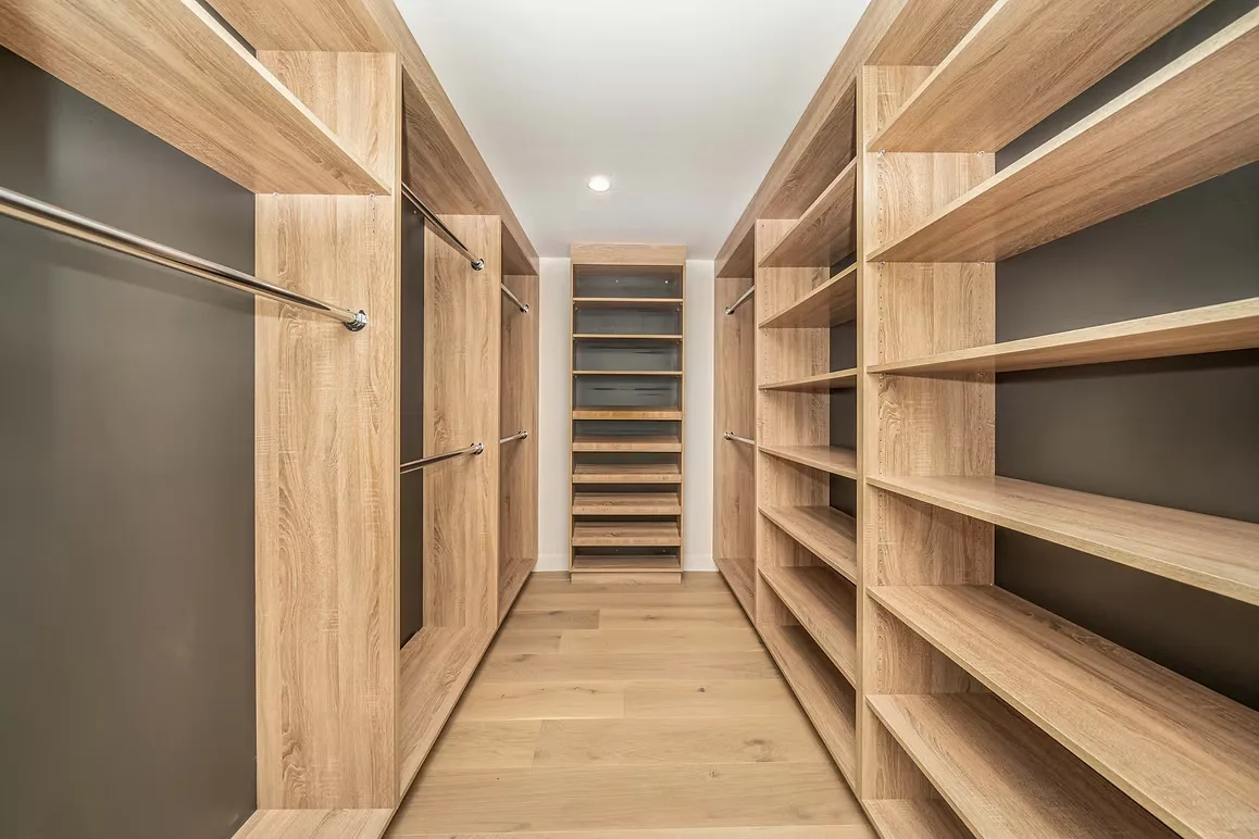 Custom walk-in closet with wooden shelves and hanging rods for ample storage space.