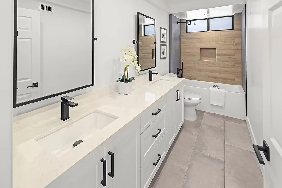 Bright bathroom with white cabinetry, modern fixtures, and a wooden shower wall.