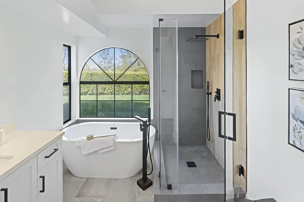 Modern bathroom with freestanding tub, spacious walk-in shower, and large window.