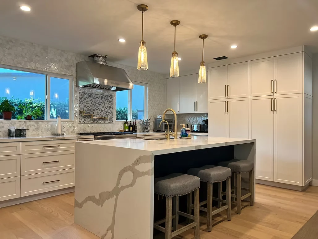 Luxury kitchen remodel with pendant lights, stainless steel appliances, and elegant backsplash.