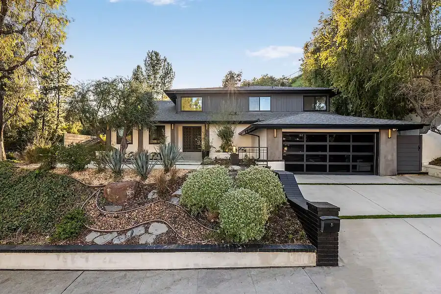 Modern home exterior with landscaped yard, featuring a stylish front entrance and clean driveway.
