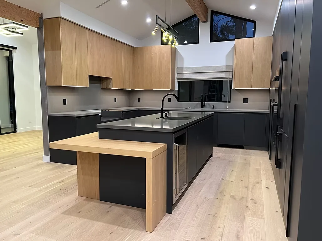 Luxury kitchen remodel with two-tone cabinetry, sleek black fixtures, and modern stainless steel appliances.