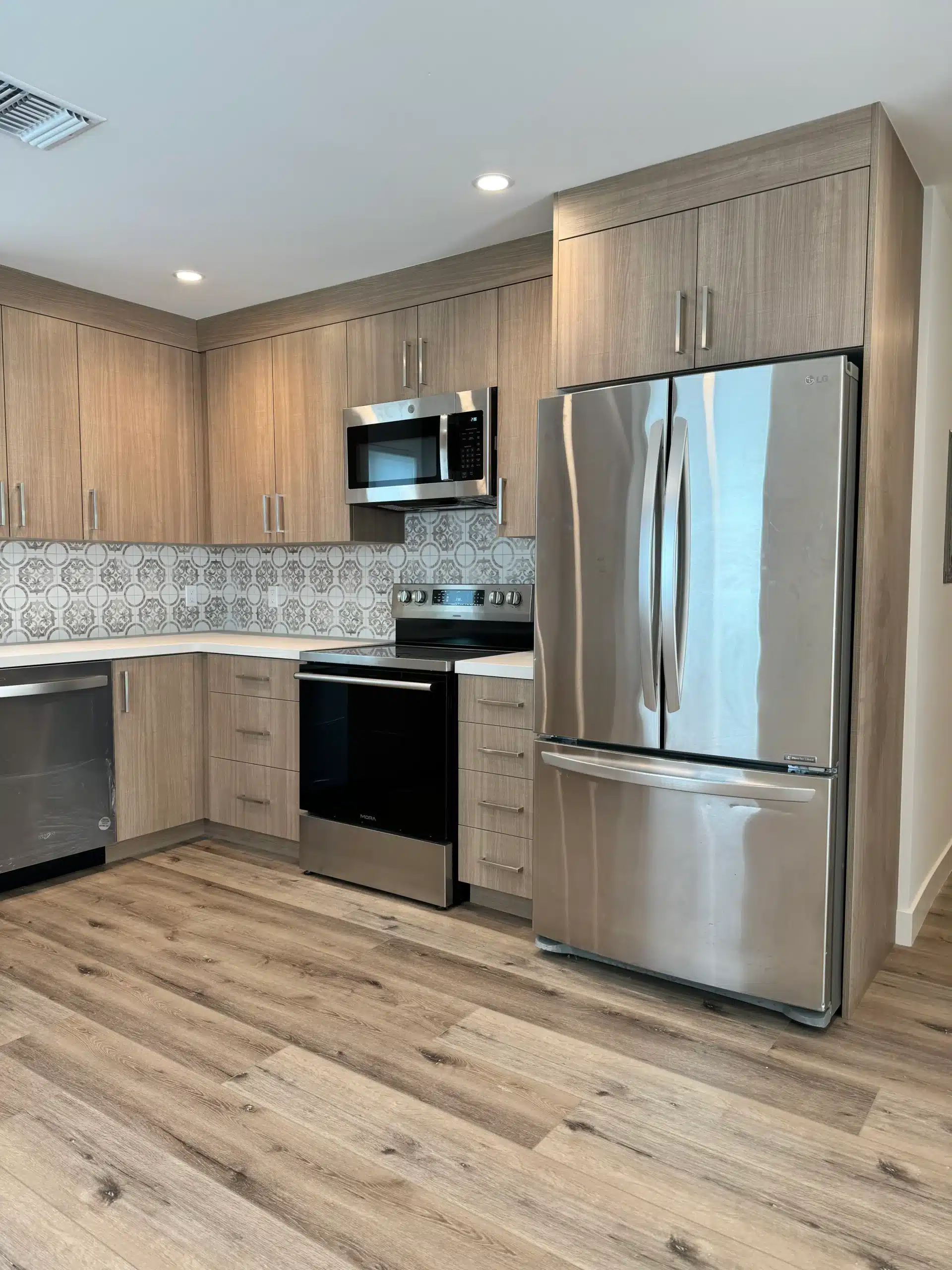 Vertical close-up shot focusing on the range, microwave, and adjacent refrigerator stack.