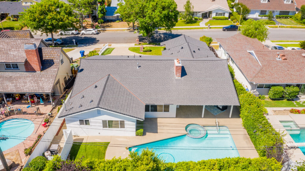 An elevated view of the backyard featuring a swimming pool, integrated hot tub, and a covered patio area.