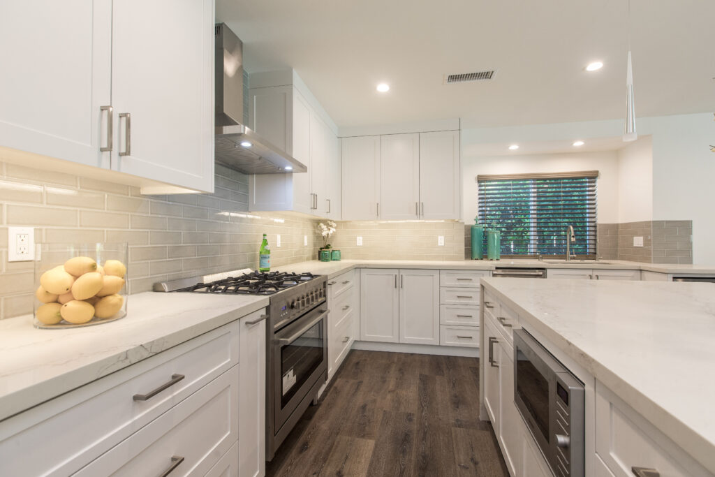 Detail shot of the kitchen counter, gas stovetop, and white tiled backsplash under bright LED lighting.