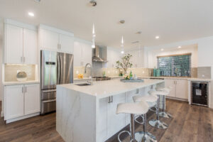 An angled view of the kitchen showing the marble island, stainless steel refrigerator, and wine cooler.