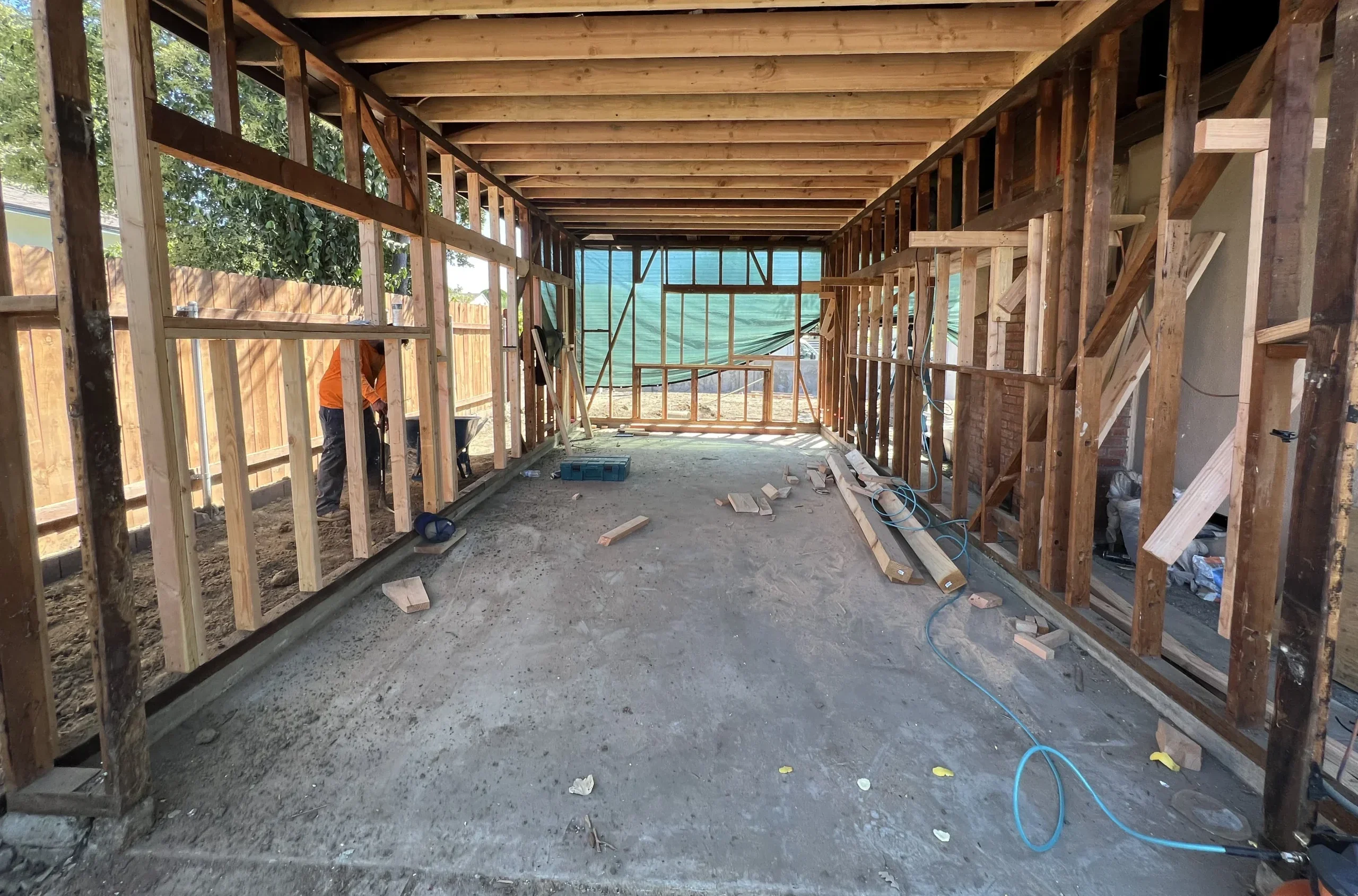 Open wood timber framing and exposed ceiling joists of a residential room extension under construction.